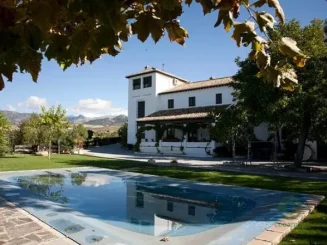 Finca de recreo con piscina y casa tradicional rodeada de naturaleza y vistas a la sierra.