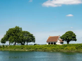 Vivienda rural entre árboles y río, imagen ideal para tratar el precio del suelo rústico.