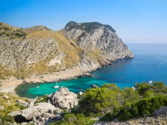Paisaje costero mediterráneo en Mallorca, con cala de aguas turquesas, acantilados y montaña que evocan la Sierra de Tramuntana, ideal para turismo, naturaleza y escapadas.