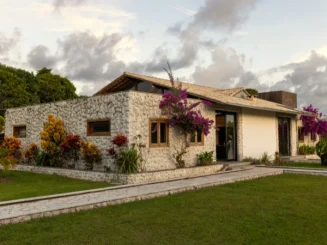 Casa moderna de piedra rodeada de jardín con flores coloridas y césped bien cuidado.